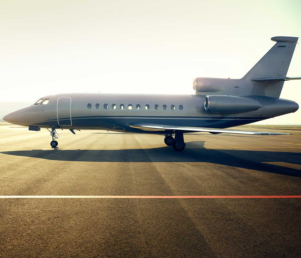 Dassault Falcon 900 private jet sitting on runway during sunrise