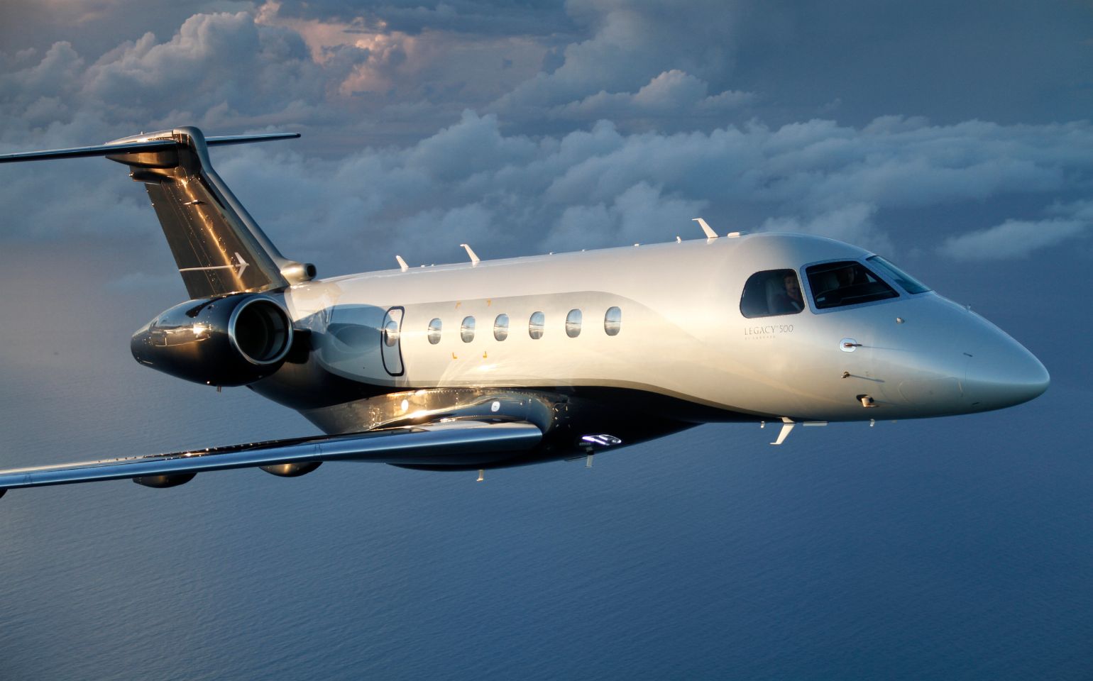 Embraer Legacy 500 private jet charter flying in sky 