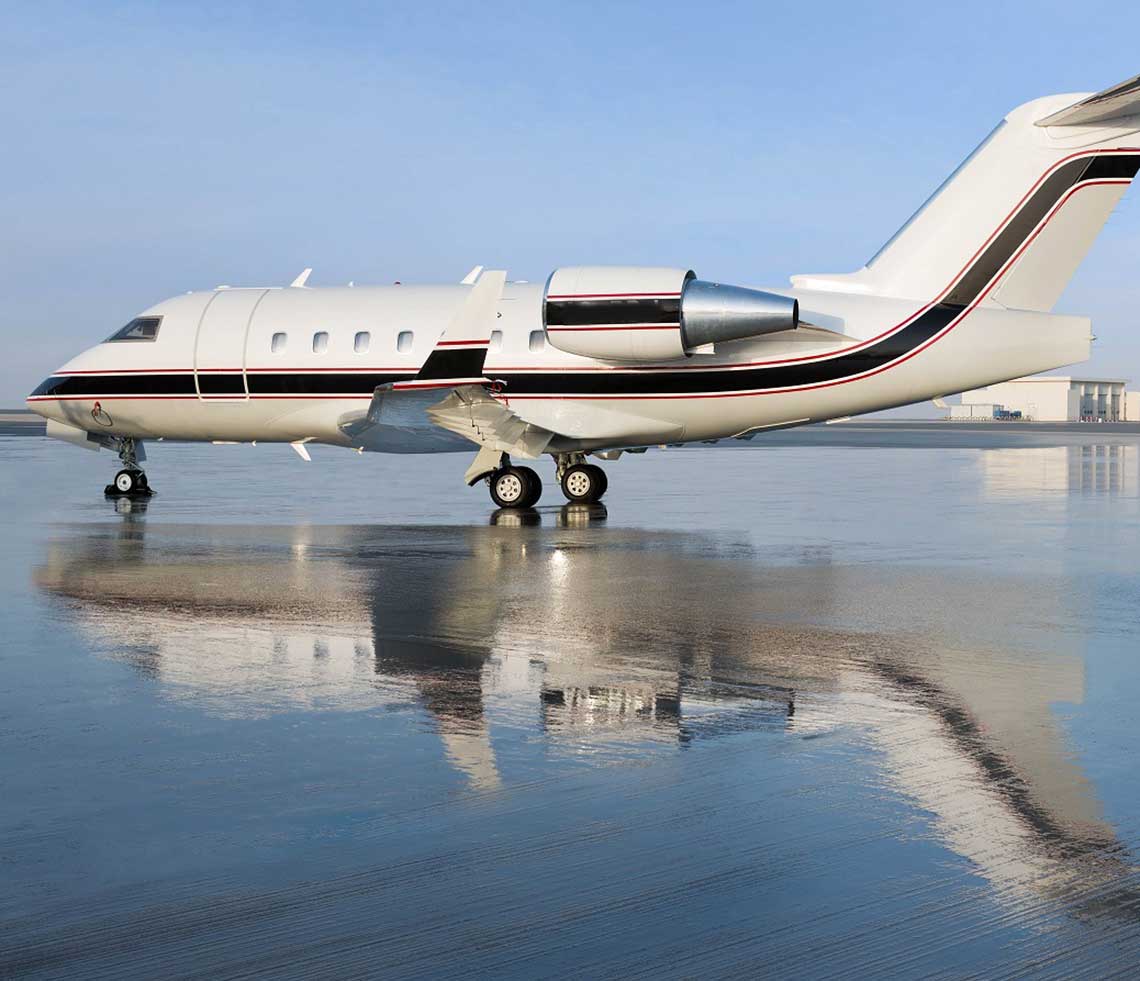Bombardier Challenger 604 private jet on airport runway with reflection